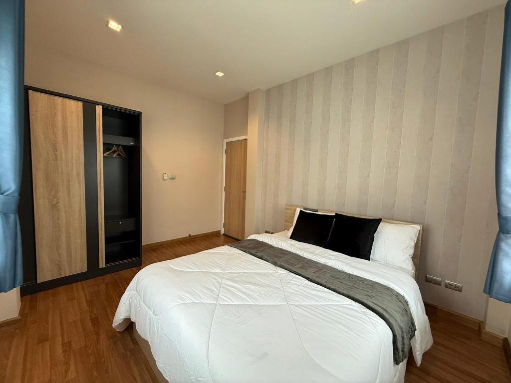 a bedroom with a large white bed with black pillows at Ssara house near suvannabhumi airport in Ban Khlong Prawet