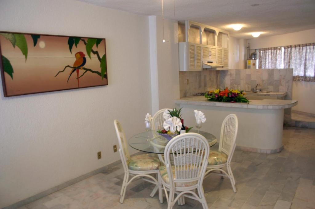une salle à manger avec une table et des chaises en verre dans l'établissement Hotel Suites Jazmín Acapulco, à Acapulco