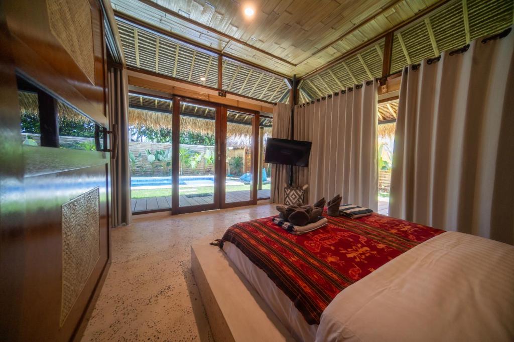 a bedroom with a bed in a room with windows at Villa Kesambi in Gili Air
