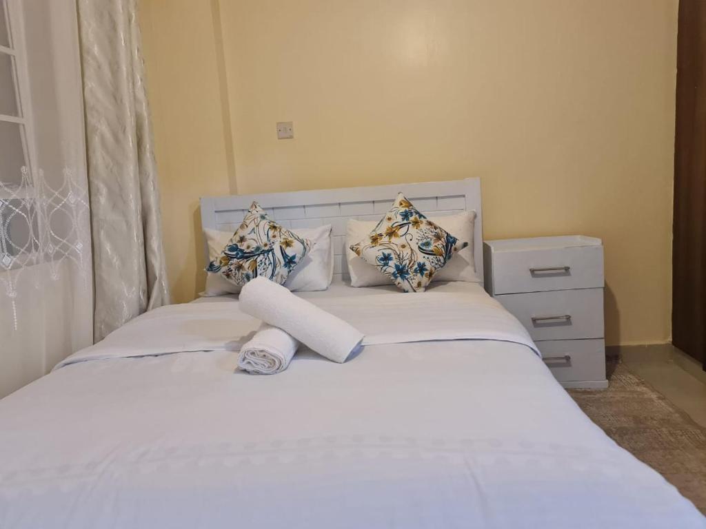Un dormitorio con una cama con sábanas y almohadas blancas. en Lawrence place, en Nairobi