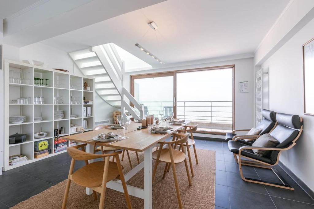 a dining room with a table and chairs and a large window at Seahouse by BLOSS, appartement met magistraal zeezicht met 2 terrassen in Wenduine