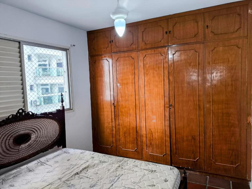 ein Schlafzimmer mit einem Bett und einem großen Holzschrank in der Unterkunft Apartamento Guarujá in Guarujá