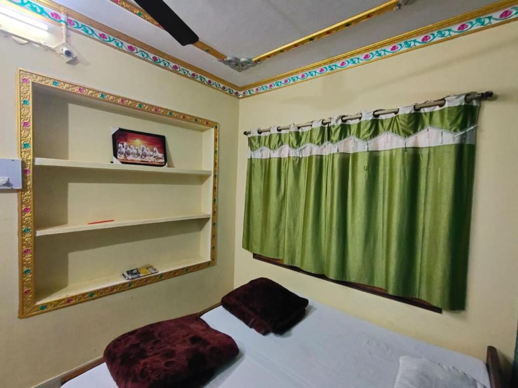 a bedroom with a green curtain and a mirror at Hotel Shanti rest house - शांति विश्राम गृह Gaya in Gaya