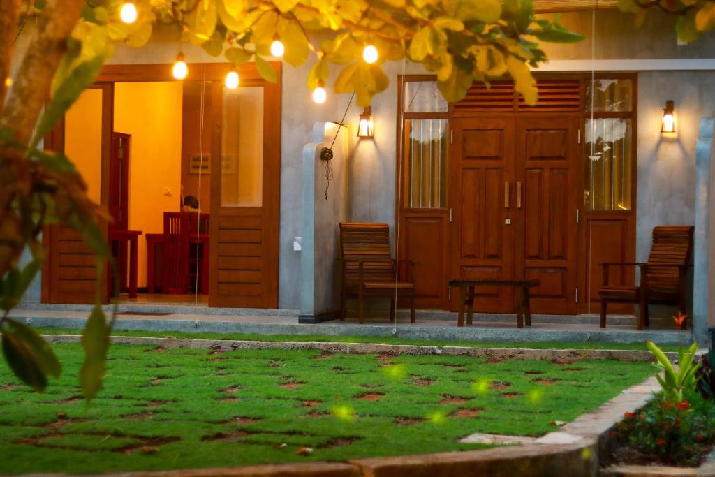 ein Haus mit Holztüren und einem Garten mit Rasen in der Unterkunft Colours Beach in Induruwa