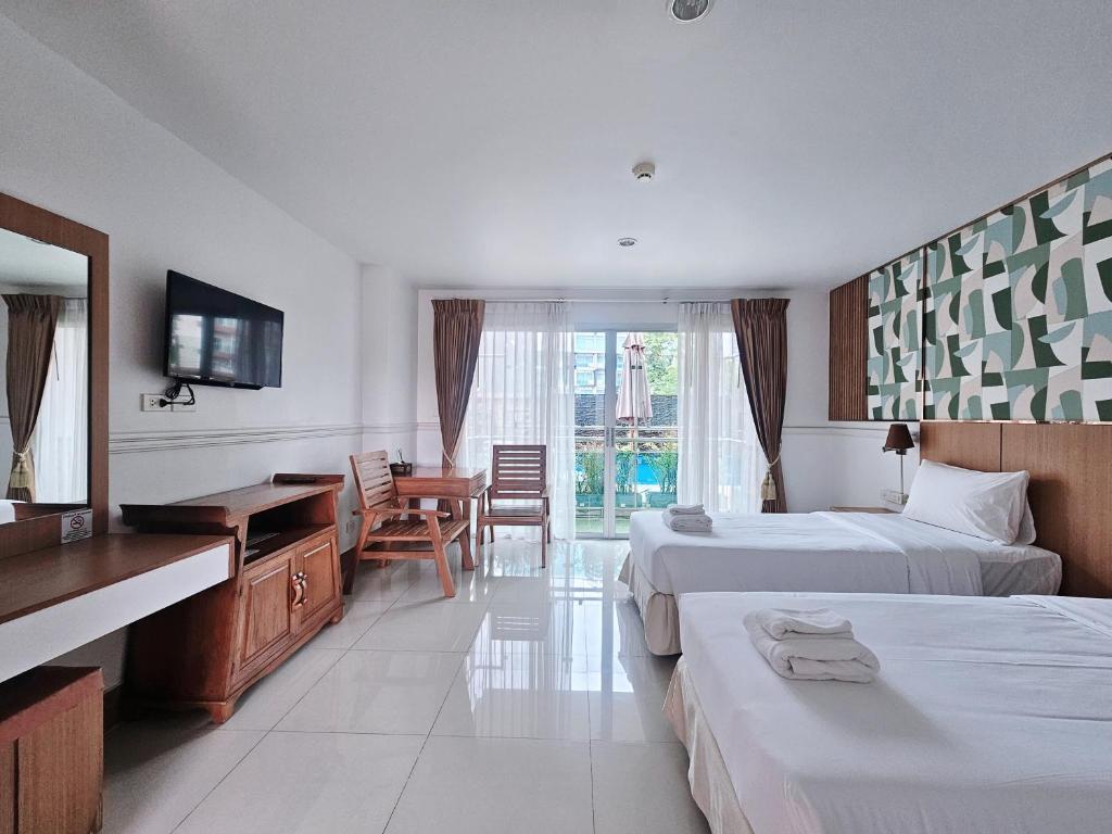 a hotel room with two beds and a desk at Nanthana Villa in North Pattaya