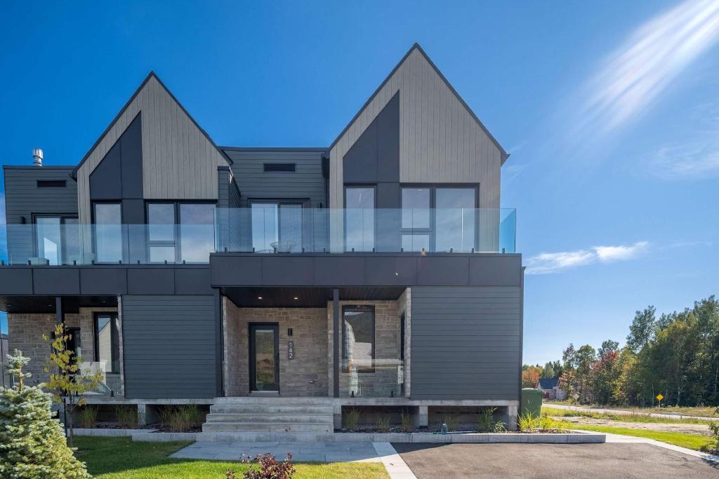 a large house with a glass facade at Absolute Comfort with Spa & Game Room - Base Camp in Beaupré