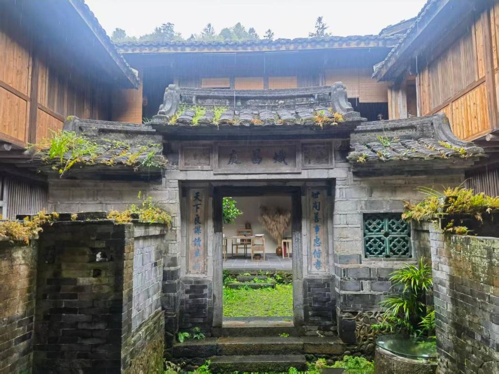 an entrance to a stone building with plants at Tsingpu Tulou Retreat 青普文化行馆 南靖土楼店 in Nanjing