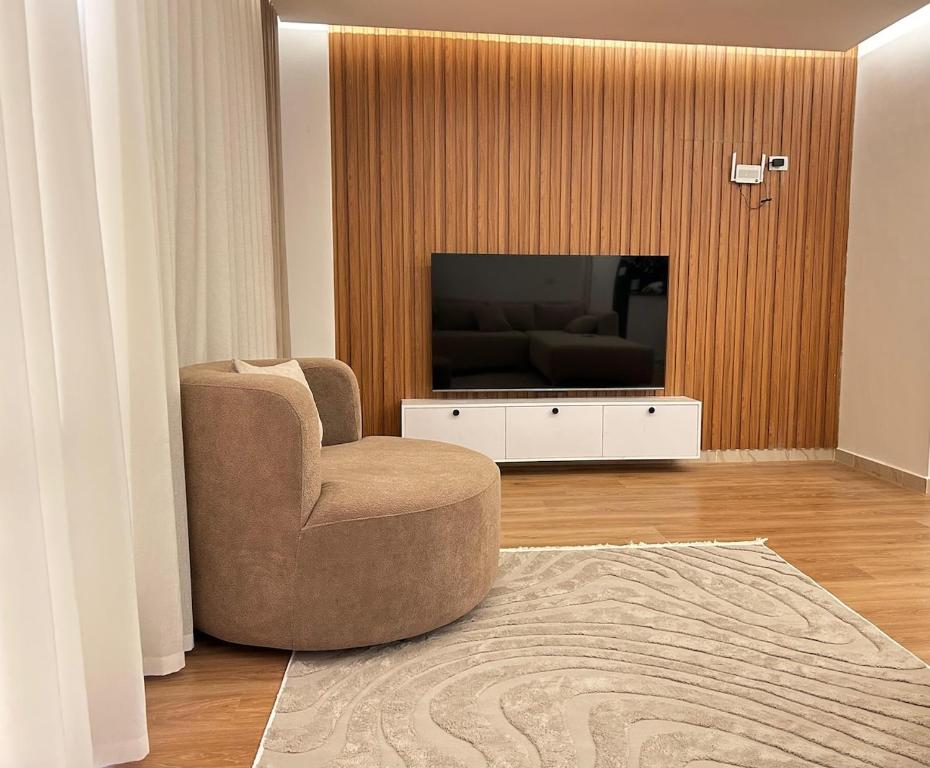 a living room with a chair and a television at Luxurious and hotel-like accommodation with garden view in New cairo