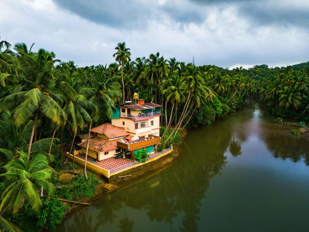 una casa in mezzo a un fiume con palme di Nadi Teera Homestay a Honāvar