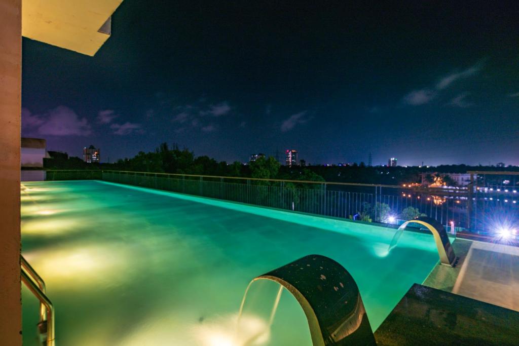 a swimming pool at night with a view of the city at Crescent Luxe Stays in Ernakulam