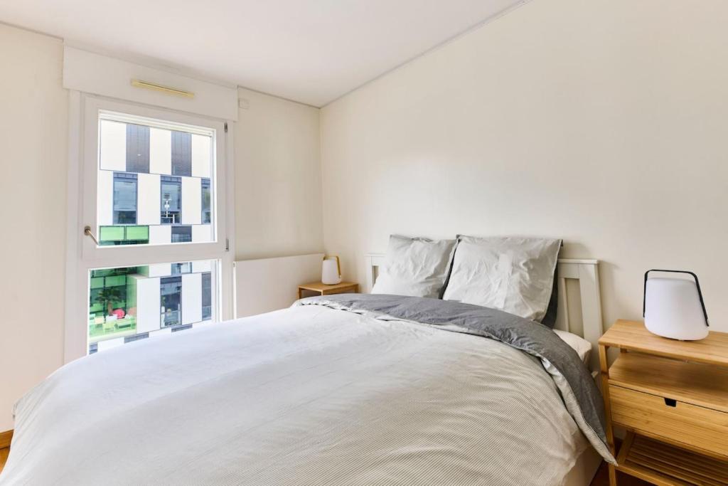 a white bedroom with a bed and a window at Bright apartment paris 19-metro 7 in Paris