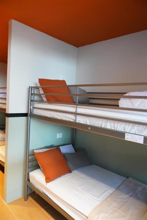 an empty bunk bed with an orange pillow on it at Nitra Hostel in Ban Nong Chaeng