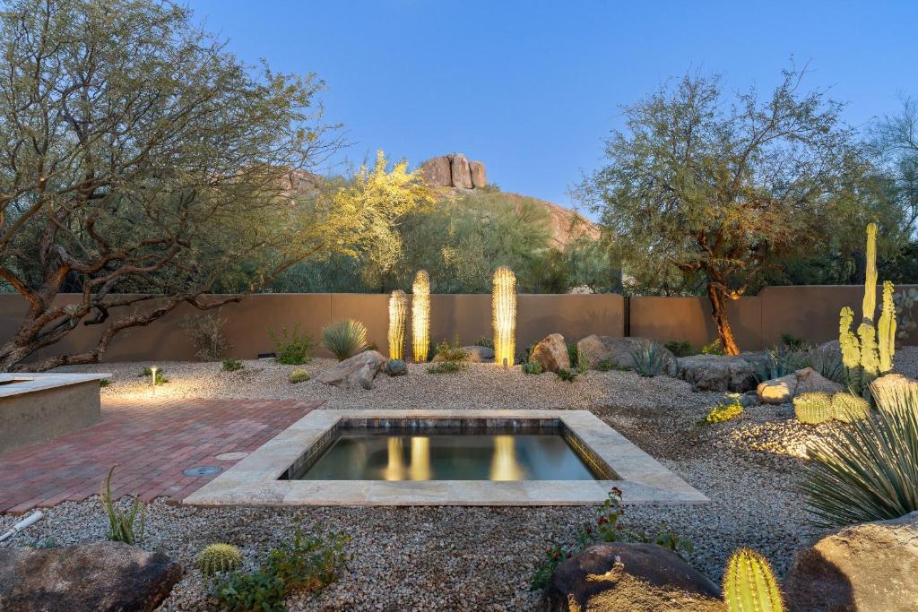 a garden with cacti and a pond in the middle at Serenity and southwest charm views hot tub. in Cave Creek
