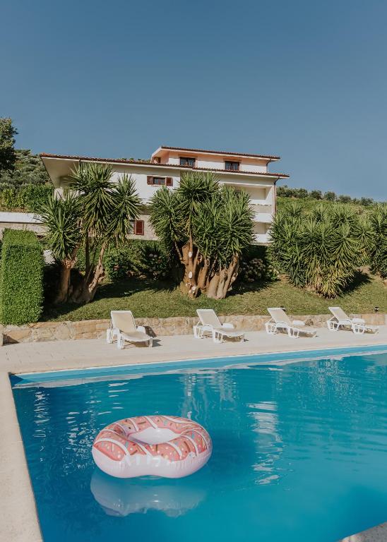 a swimming pool with a red raft in the water at Jerónimos Garden & Pool Villas in Lamego