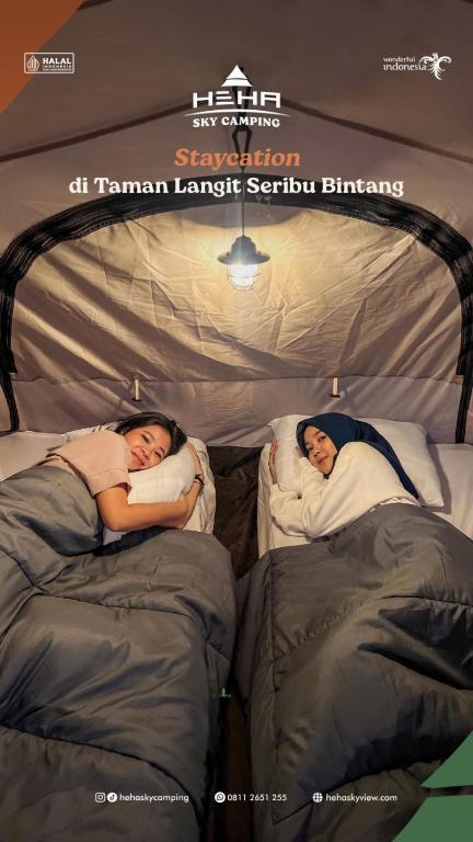 PatukにあるHeHa Sky Campingのテント内のベッドで2名が寝台に寝ています。