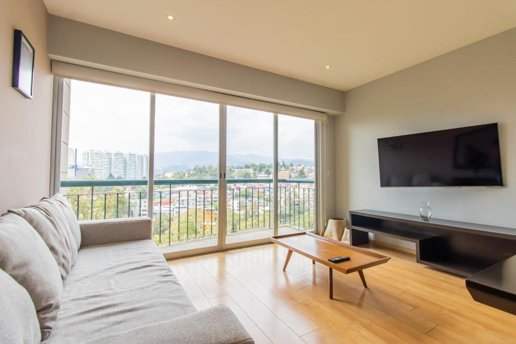 Una sala de estar con un sofá y una ventana grande. en Capitalia Luxe 1BR Stay with Top Features, en Ciudad de México