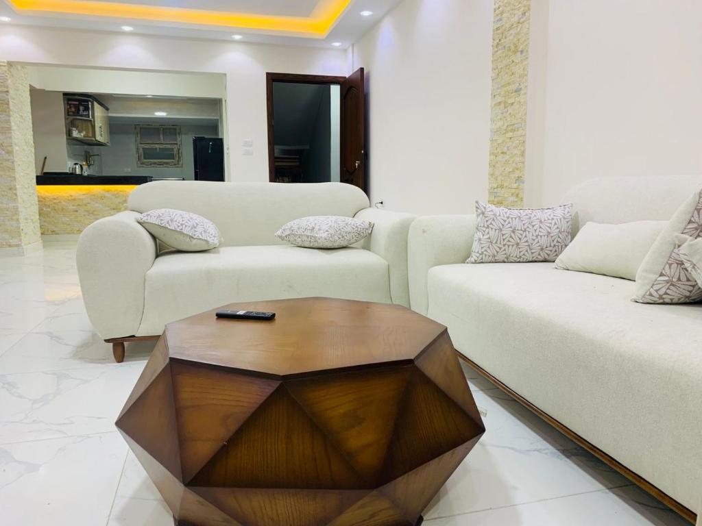 a living room with two couches and a wooden table at فيلا بقريه جرين بيتش 4 غرف وحمام سباحة خاص تشطيب السنه فرش مودرن in El Alamein