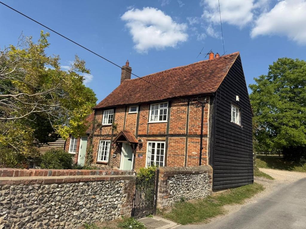 ein altes Backsteinhaus mit einer Steinmauer in der Unterkunft Pretty 2 Bedroom Cottage in Skirmett with Parking in Turville