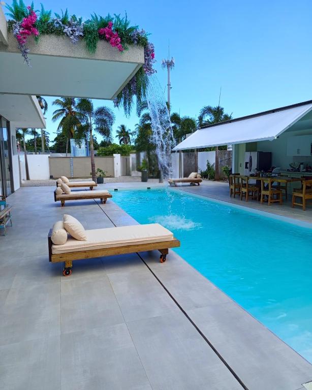 ein Pool mit zwei Liegestühlen und einem Springbrunnen in der Unterkunft Villa Modena in Las Terrenas
