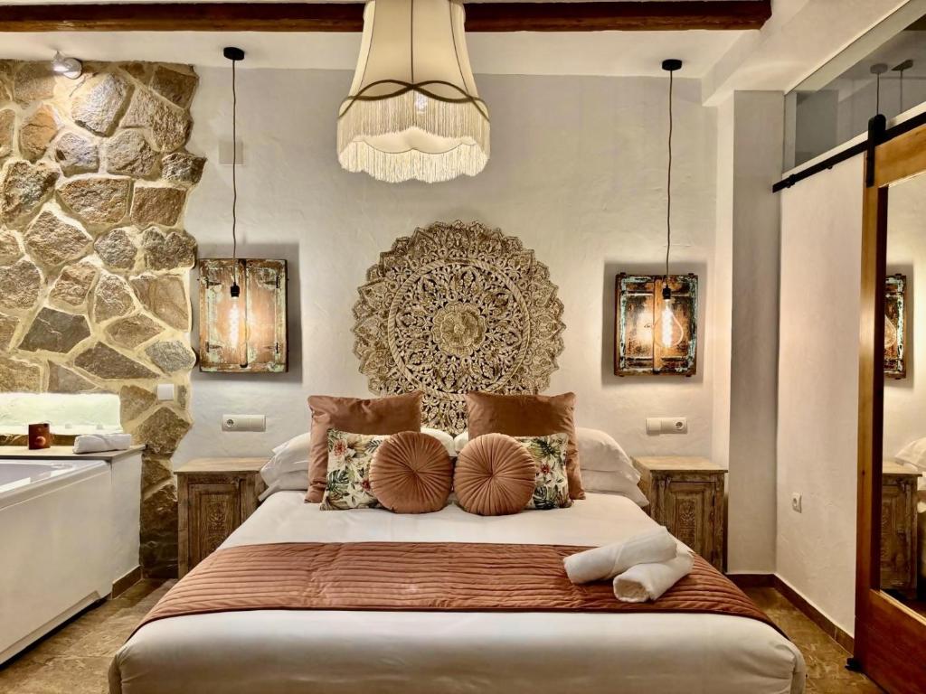a bedroom with a large bed and a stone wall at Al Zahra Suites in Zahara de la Sierra