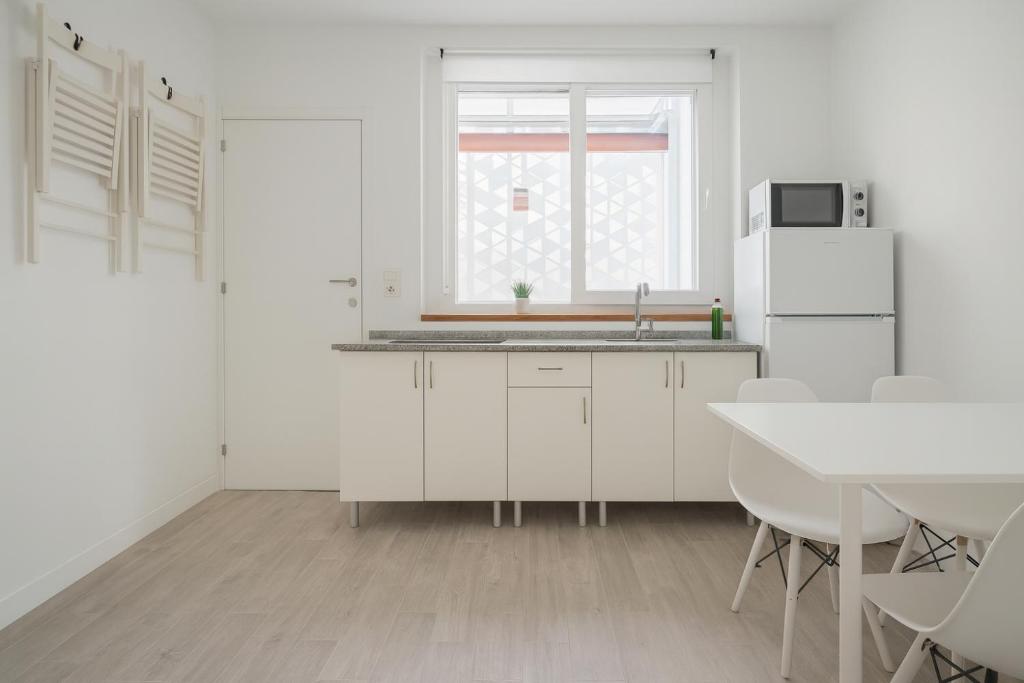a kitchen with white cabinets and a table and a window at Suite by Hawkins interior 1º A in Algeciras