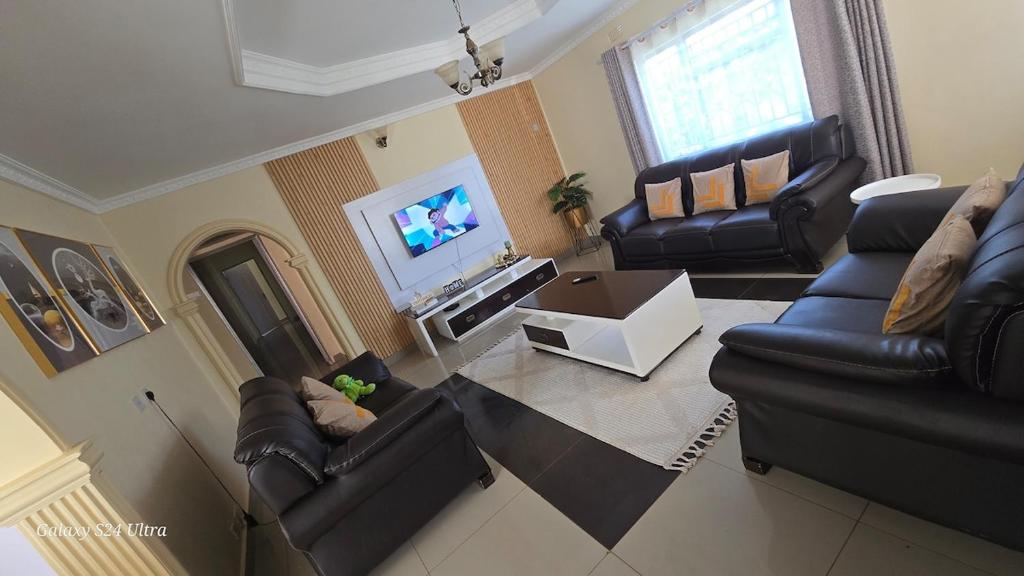 a living room with black leather furniture and a flat screen tv at FAMILY CLICK HOLMEs in Lilongwe