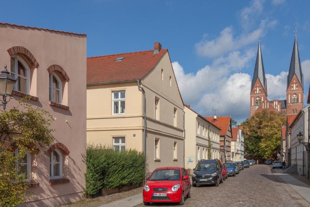 una fila de autos estacionados en una calle con edificios en Altstadt Ferienwohnung, en Neuruppin