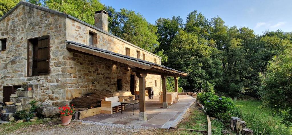 an old stone building with a porch and trees at Casa Rural Angostina in Carcabal