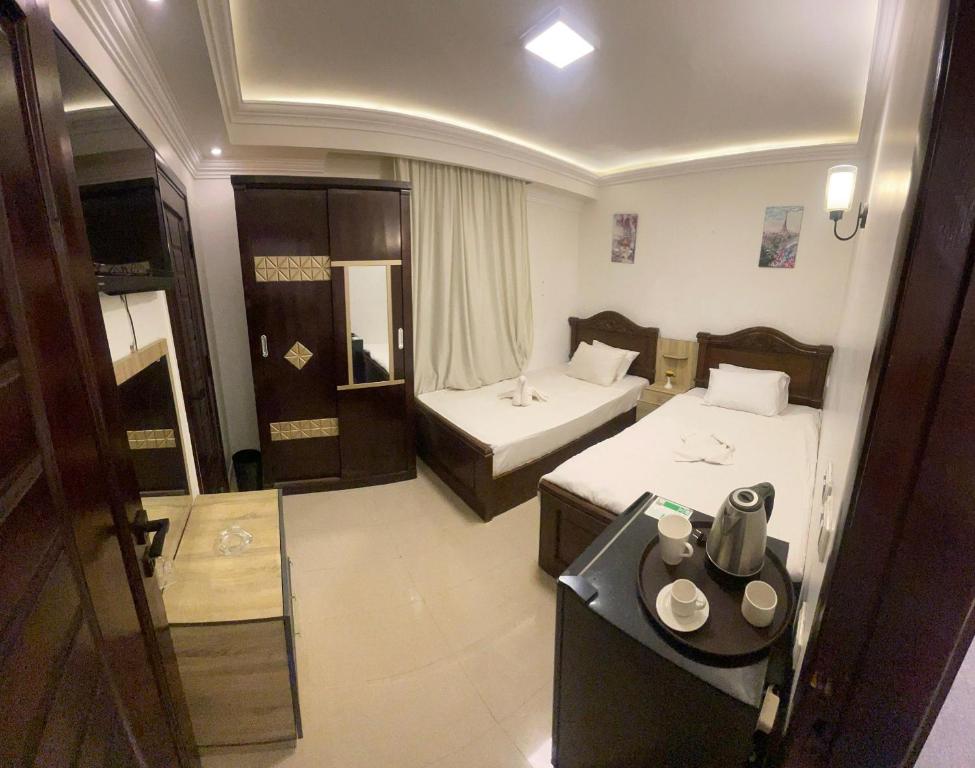 une chambre d'hôtel avec deux lits et une table dans l'établissement Pearl pyramids Inn, au Caire
