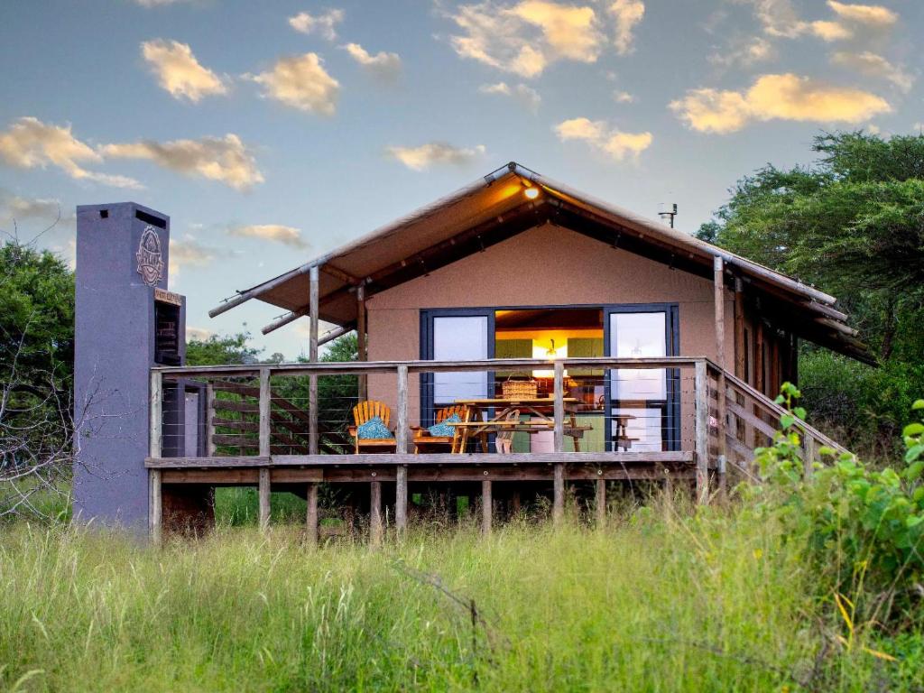 a small house with a large deck in a field at AfriCamps at White Elephant Safaris in Pongola Game Reserve