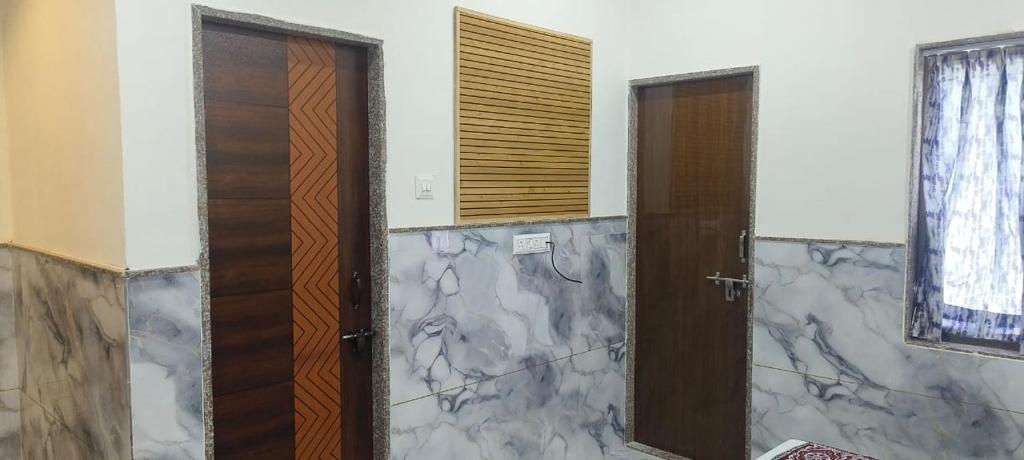 two wooden doors in a room with marble walls at RK Lodging in Phaltan