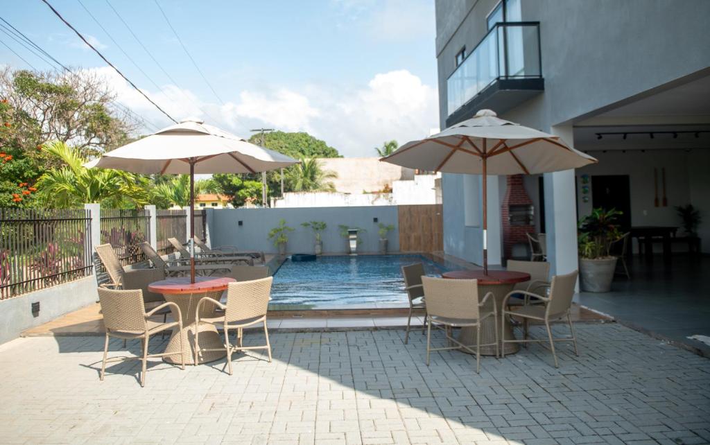 a patio with tables and chairs and umbrellas at Apto c Churrasqueira e Piscina a 100m da Praia in São Bento