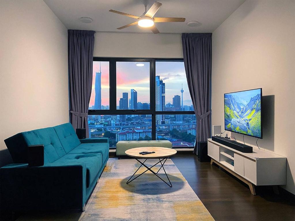 a living room with a blue couch and a television at La Gente Comfy Stay 2r2b Velocity - Kl City View in Kuala Lumpur