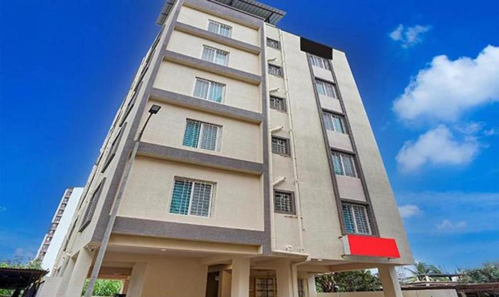 a tall white building with a red sign on it at FabHotel Seven Elite in Pune