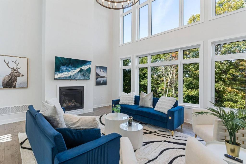 a living room with blue furniture and windows at Northern Light Retreat|HotTub|Sauna|GamesRoom in Dwight