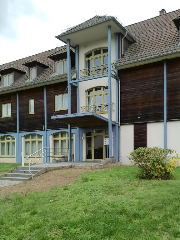an apartment building with blue columns and a yard at Pension Am Seeberg in Alt Zeschdorf