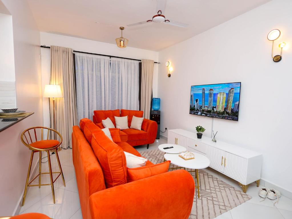 a living room with orange chairs and a couch at Cosy 2 Bedroom at Ganjoni near the landmark site at Pembe za Ndovu - Elephant Task in Mombasa