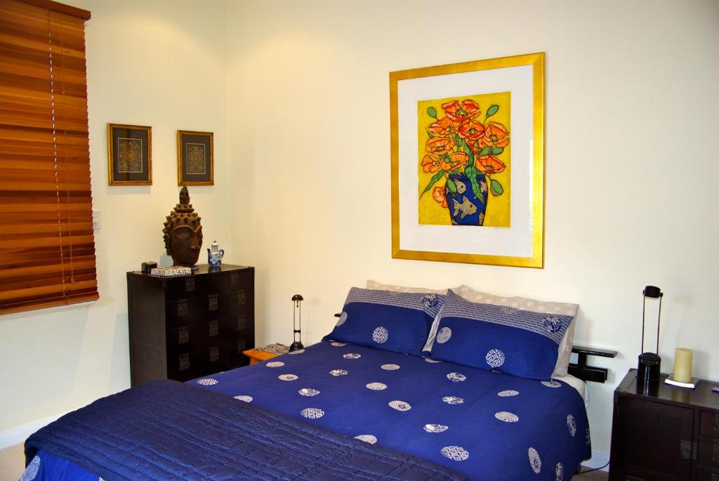 桑迪灣的住宿－十一小莊園住宿加早餐旅館，卧室配有蓝色的床和墙上的绘画作品