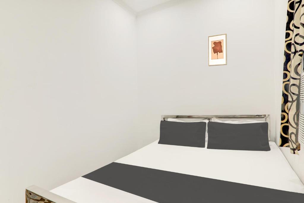 a white bedroom with a bed with two pillows at Hotel O Relax Inn in Patna