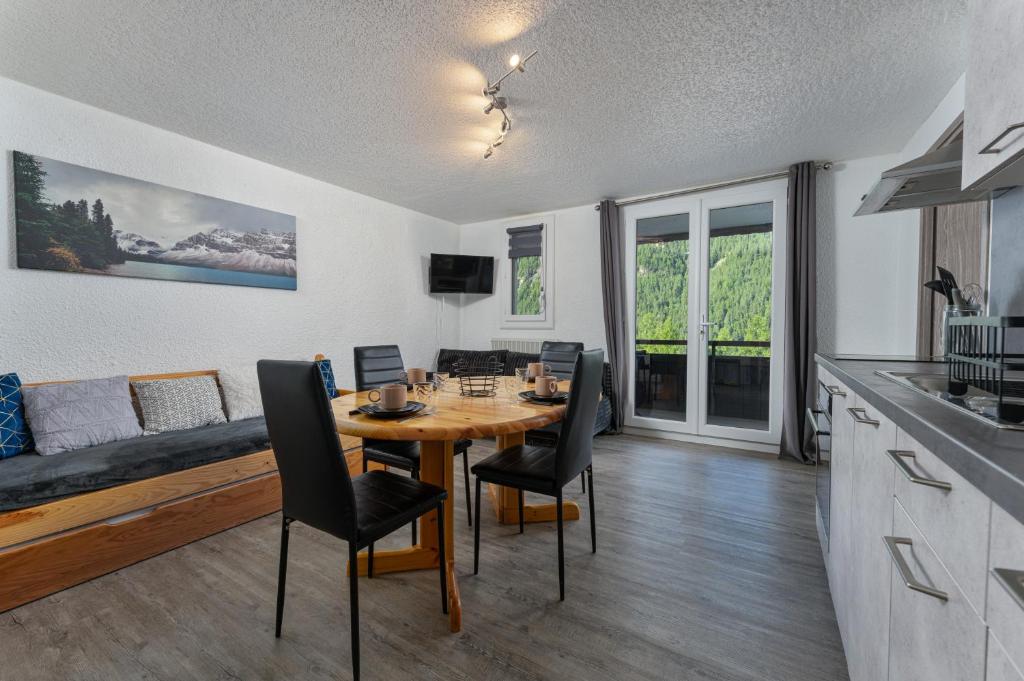 eine Küche und ein Esszimmer mit Tisch und Stühlen in der Unterkunft Les Anémones 6 places in Les Orres