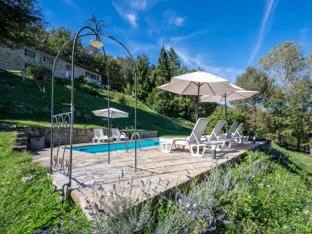 a group of chairs and umbrellas next to a pool at Apartment Appartamento Galli by Interhome in Monastero Bormida