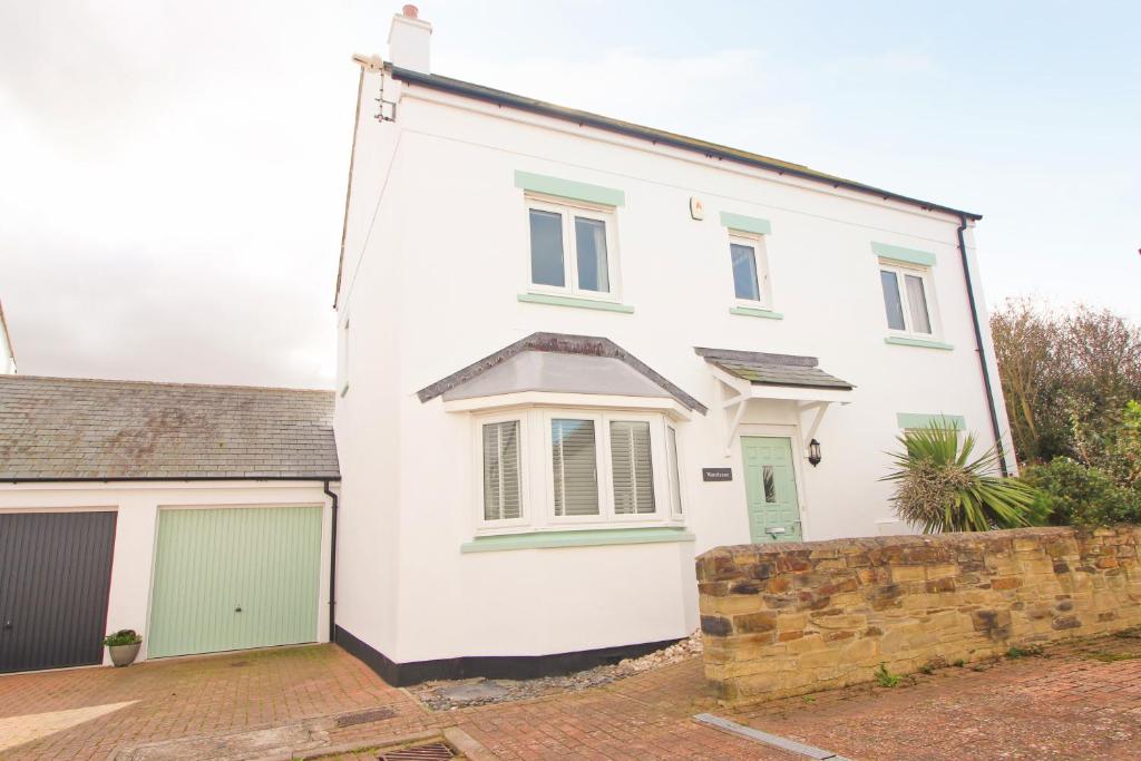 a white house with green doors and a garage at MODERN HOLIDAY HOME central St Merryn in Saint Merryn