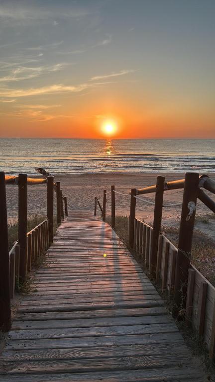 a wooden boardwalk leading to the beach at sunset at Oliva Sol Apartment in Oliva