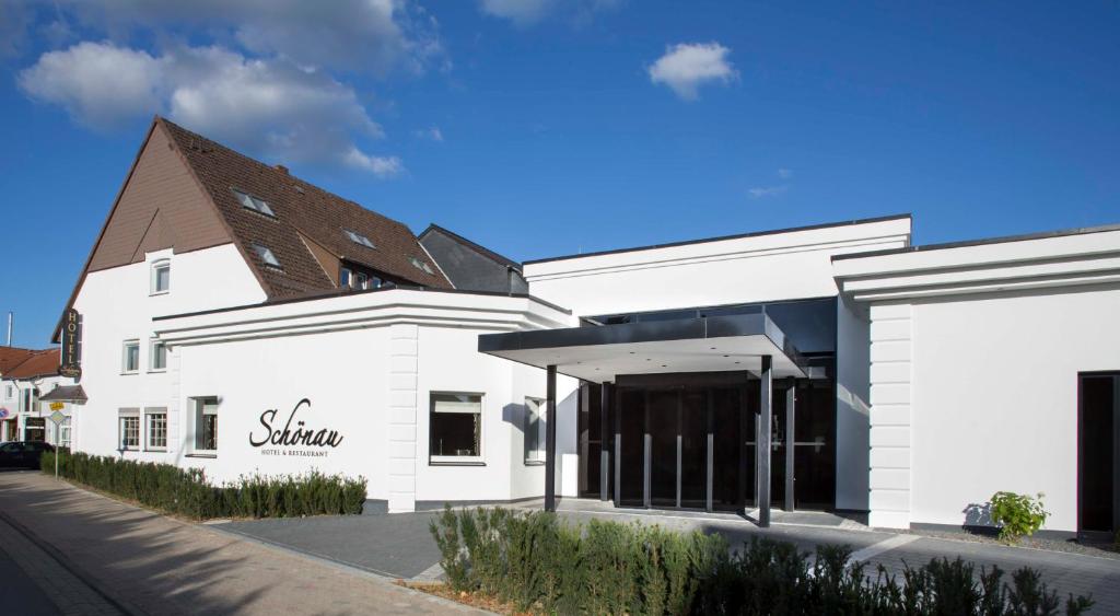 a white building with a brown roof on a street at Hotel & Restaurant Schönau in Peine