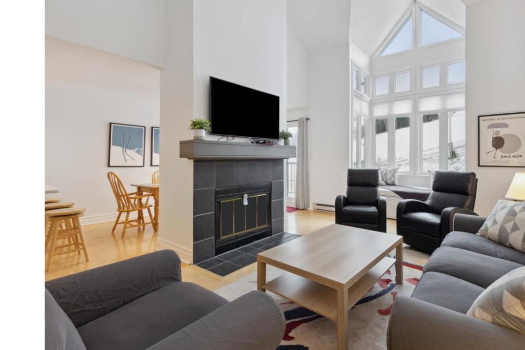 ein Wohnzimmer mit Kamin und Fernseher in der Unterkunft Slopeside Ski In Ski Out Second Floor Condo in Blue Mountains