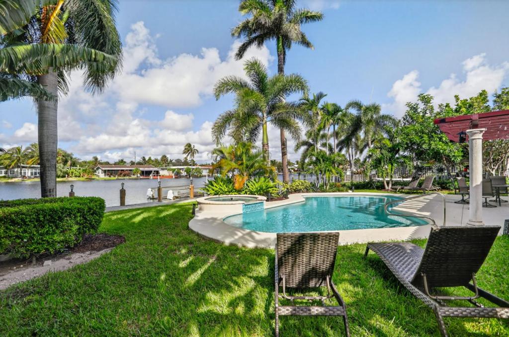 a swimming pool with two chairs and palm trees at Siena Villas in Pompano Beach