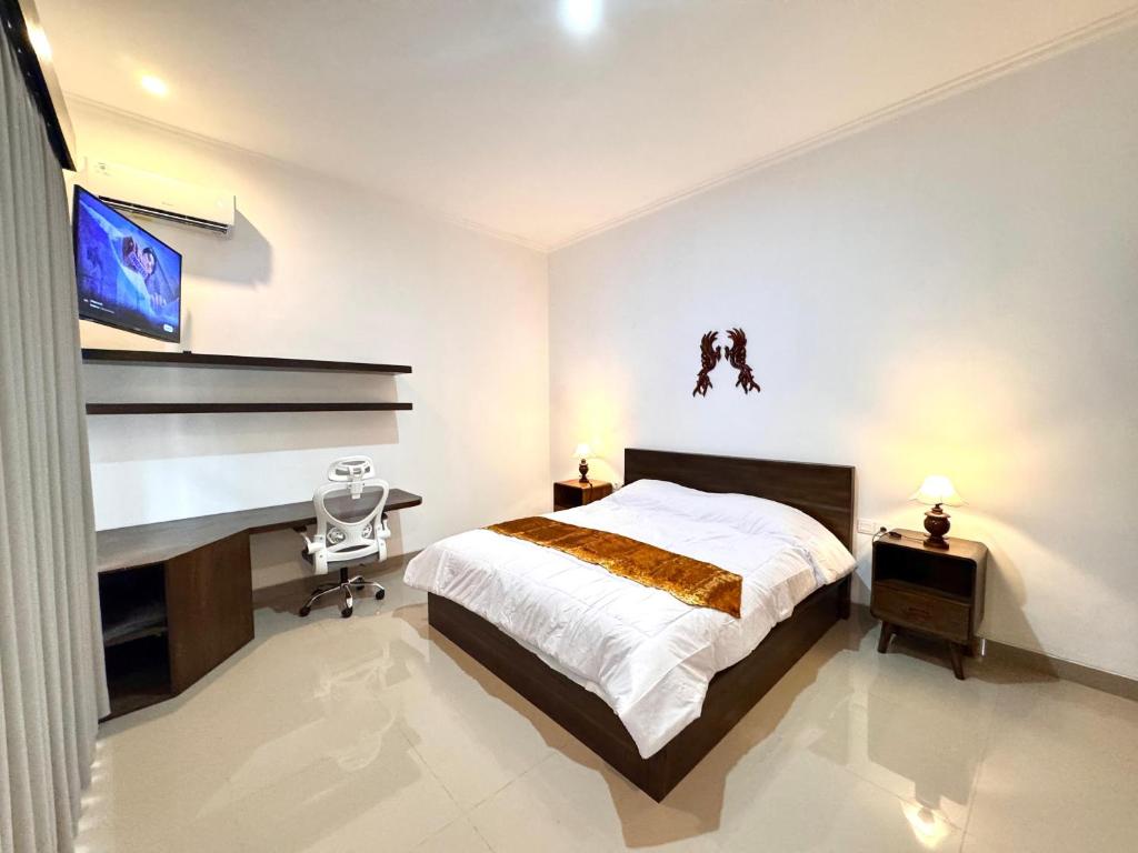 Un dormitorio con una cama, un escritorio y un televisor. en Livana Villa 02, en Kerobokan
