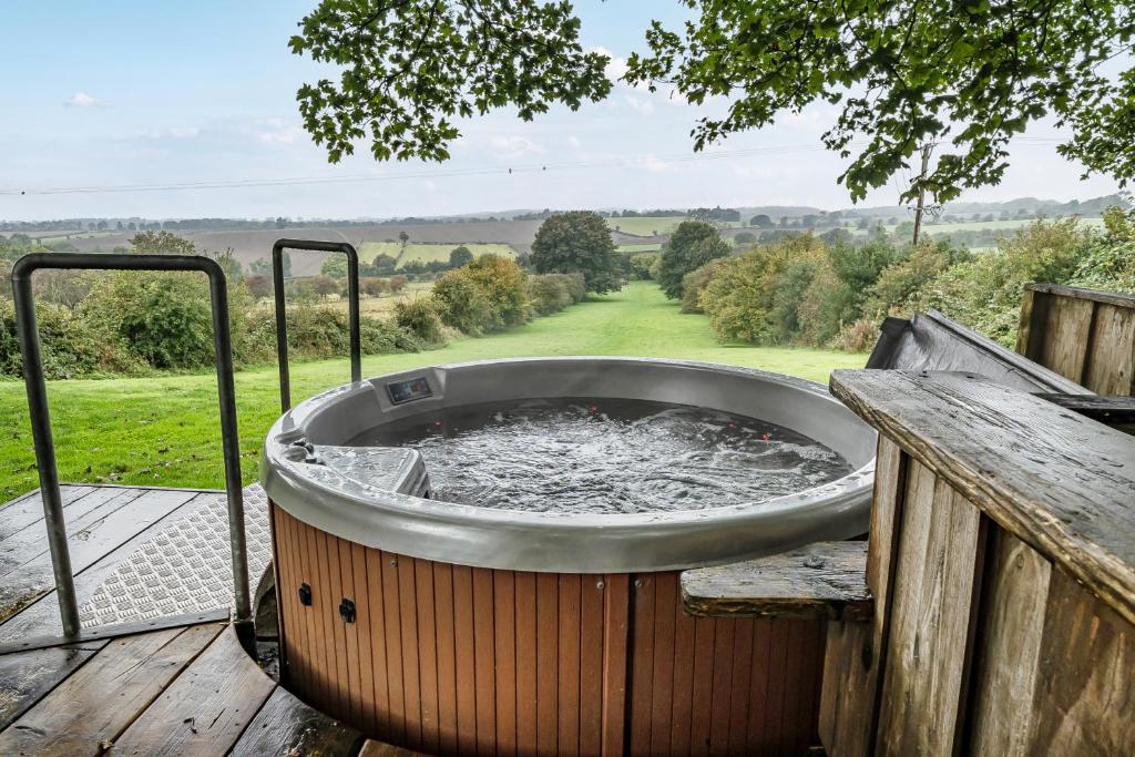 a hot tub on a wooden deck with a view at The Hide - Cosy Cabin with hot tub in Newton