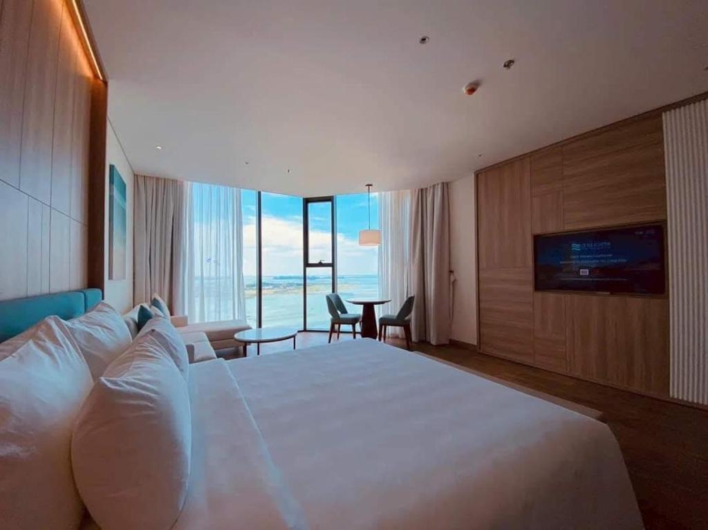 une chambre d'hôtel avec un grand lit et une télévision dans l'établissement Little Kun - A La Carte Hạ Long Homestay view Biển, à Hạ Long