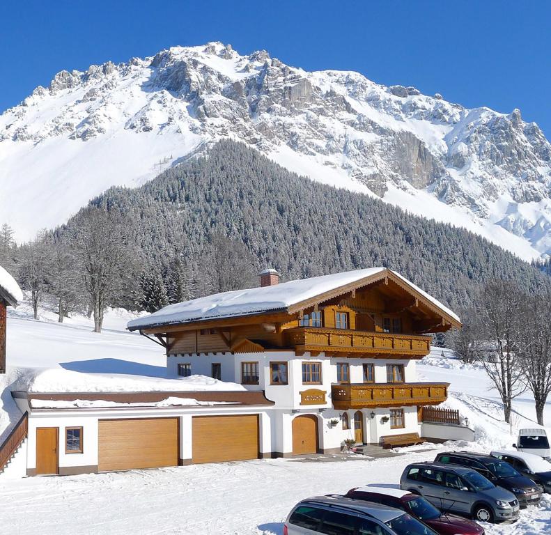 un bâtiment avec des voitures garées devant une montagne dans l'établissement Appartmenthaus Geroldhof, à Ramsau am Dachstein